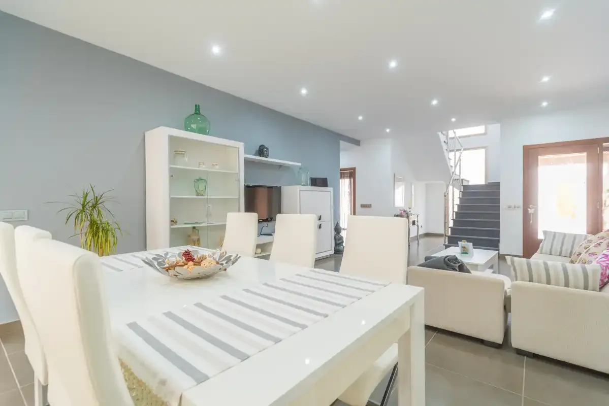 Un luminoso comedor y sala de estar con una mesa blanca y asientos.