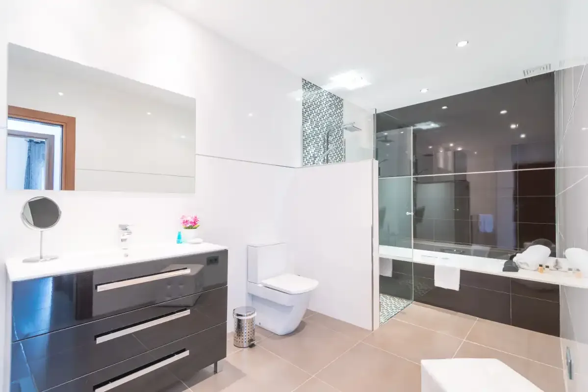 Un baño luminoso con lavabo, inodoro y ducha con mampara de vidrio.