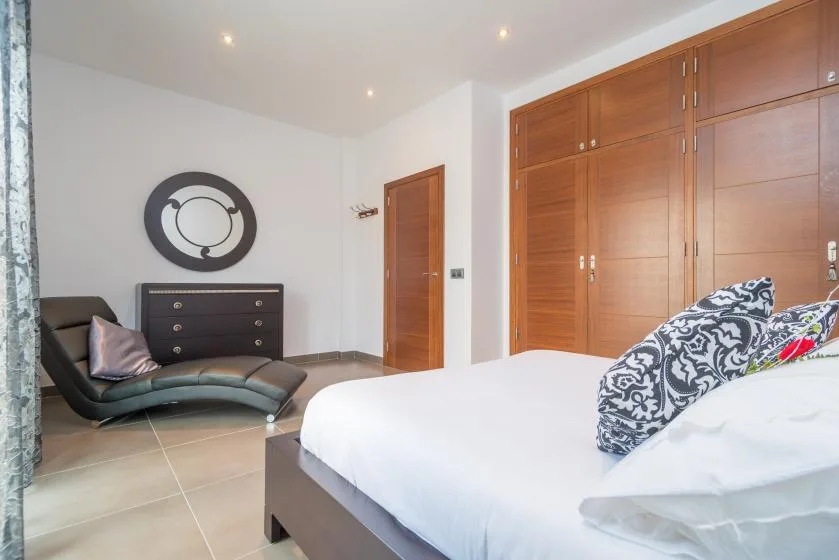Un dormitorio con una cama grande, asientos oscuros y armarios de madera.
