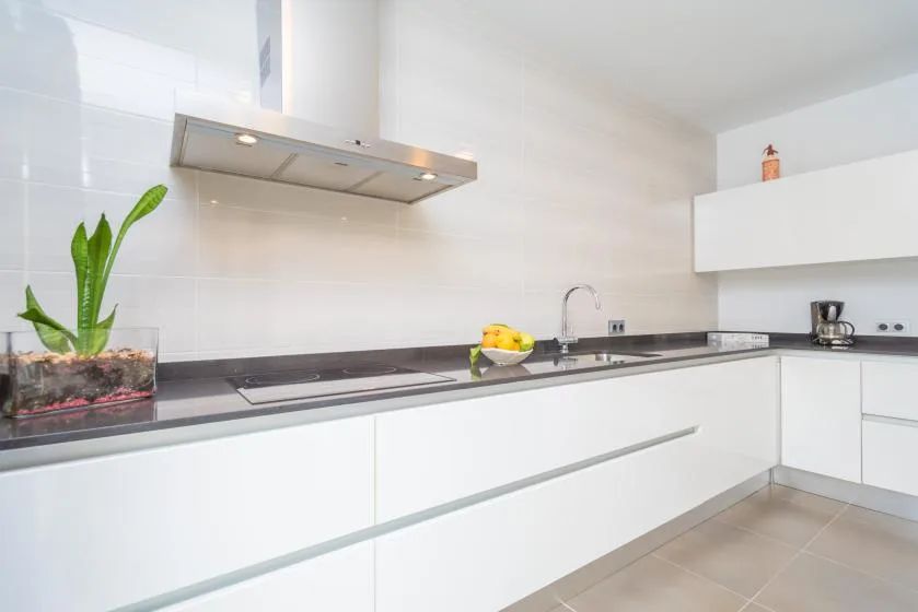 Una cocina moderna y luminosa con gabinetes blancos y una encimera larga.