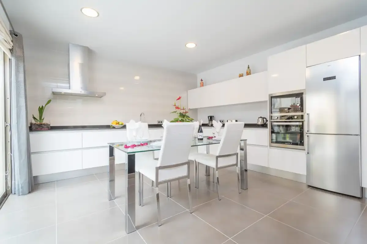 Una cocina moderna con gabinetes blancos y una mesa de comedor.