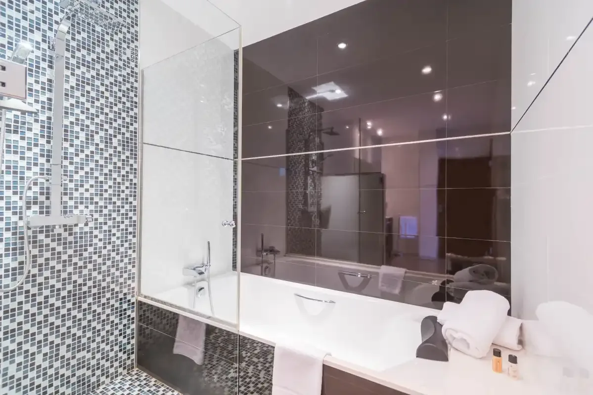 Un baño moderno con bañera y una zona de ducha con mosaicos.