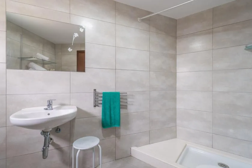 Un baño alicatado con lavabo de pared, toallero y bañera.