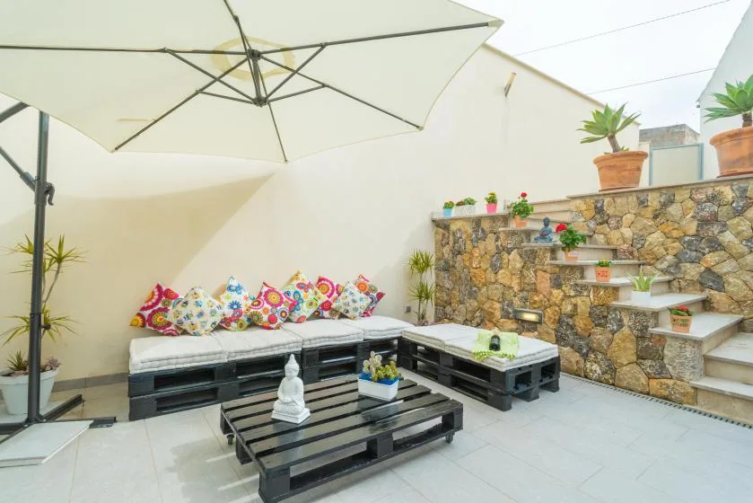 An outdoor patio seating area with colorful cushions beneath a large umbrella.