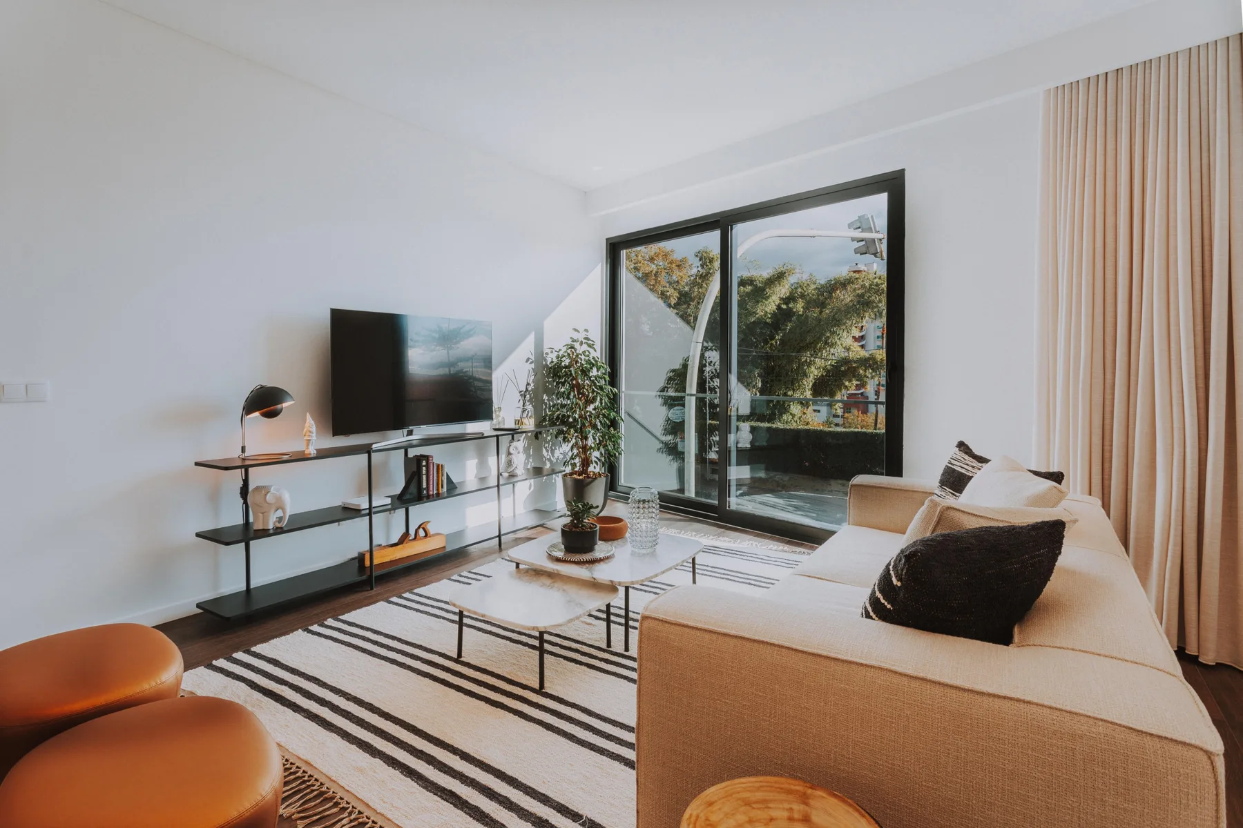 Una sala luminosa con asientos, un televisor y puertas corredizas de vidrio.