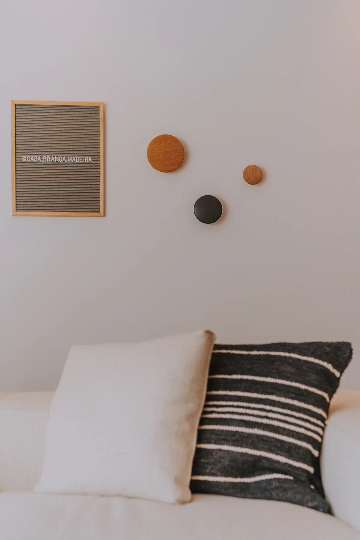 Una cama con ropa de cama blanca y dos cojines decorativos está junto a una pared clara.