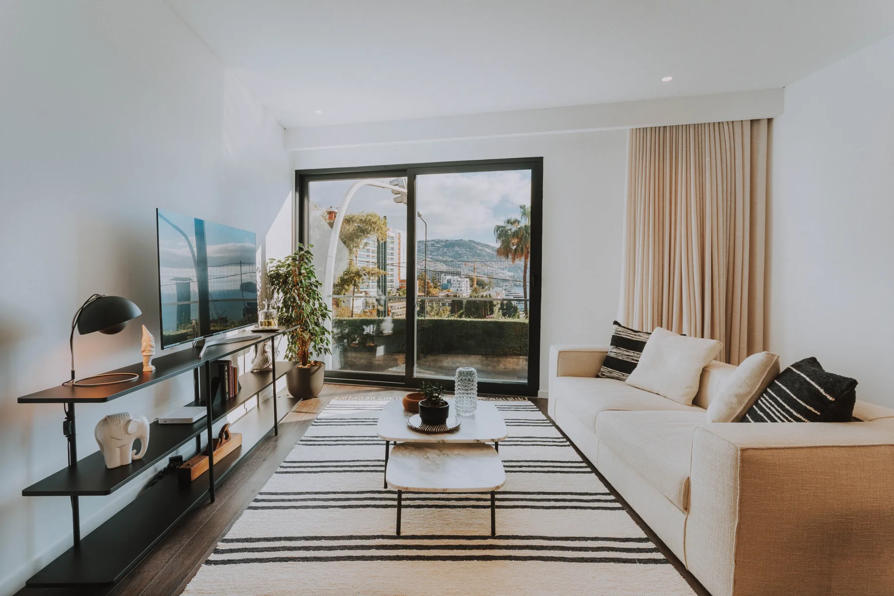 Una sala luminosa con asientos, un televisor y puertas corredizas de vidrio.