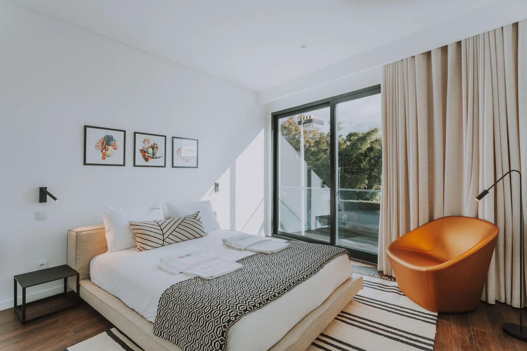 Un dormitorio con una cama junto a una puerta de cristal y una silla naranja.