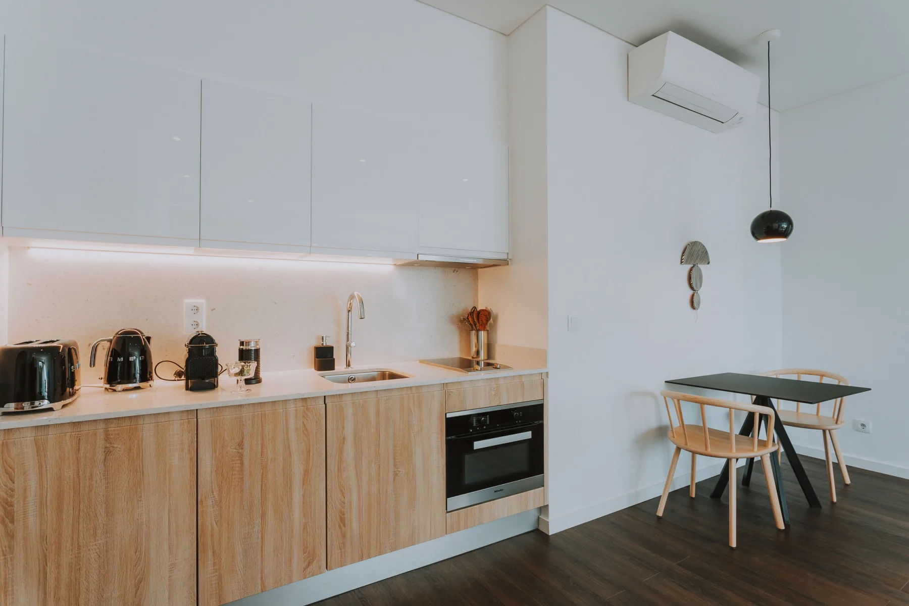 Una cocina moderna se abre a una pequeña zona de comedor con mesa y sillas.