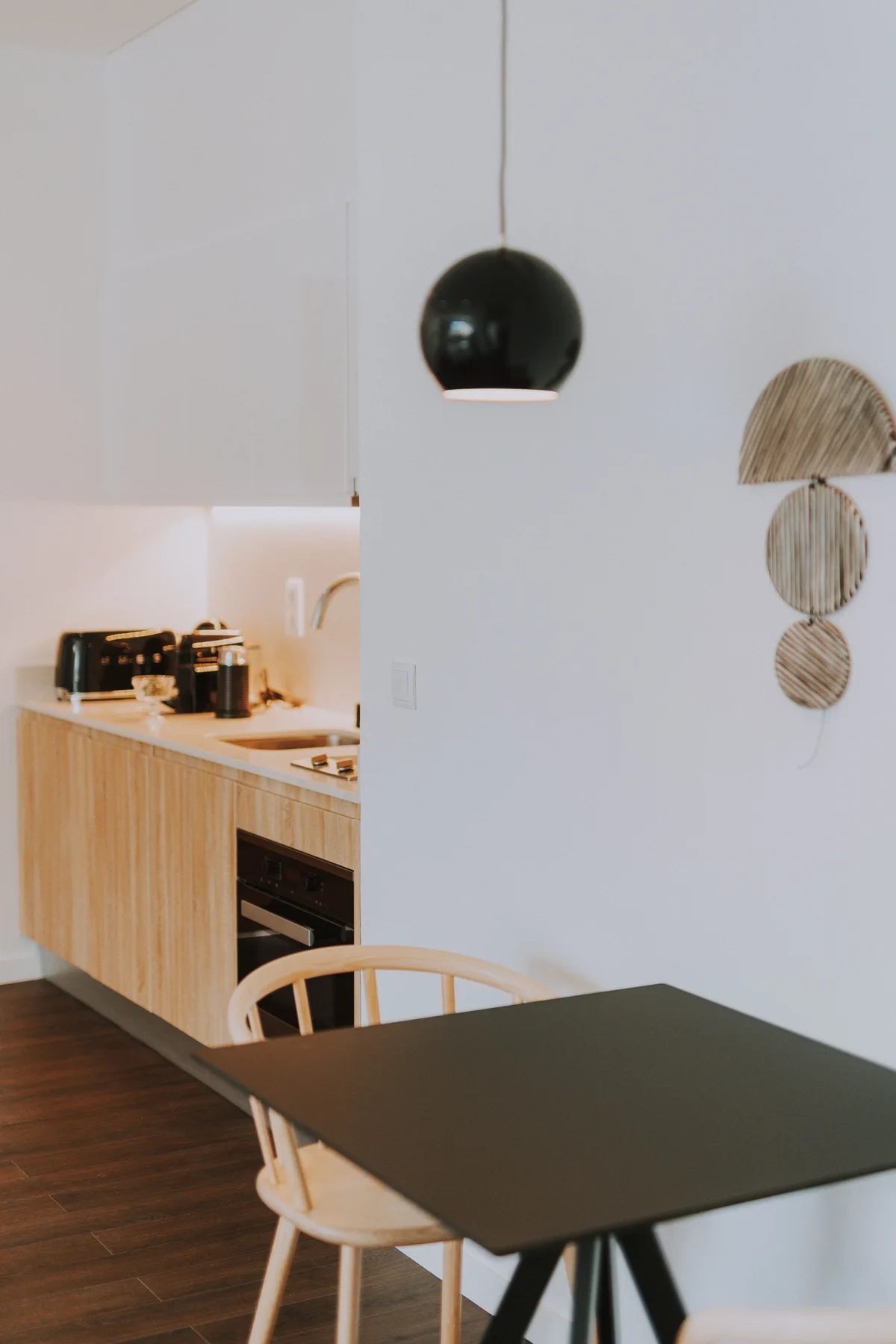 Comedor con una mesa oscura junto a una cocina compacta.