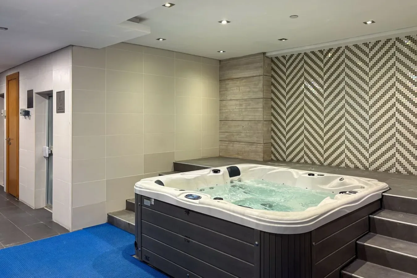 Un espacio de spa con una gran bañera de hidromasaje y paredes estampadas.