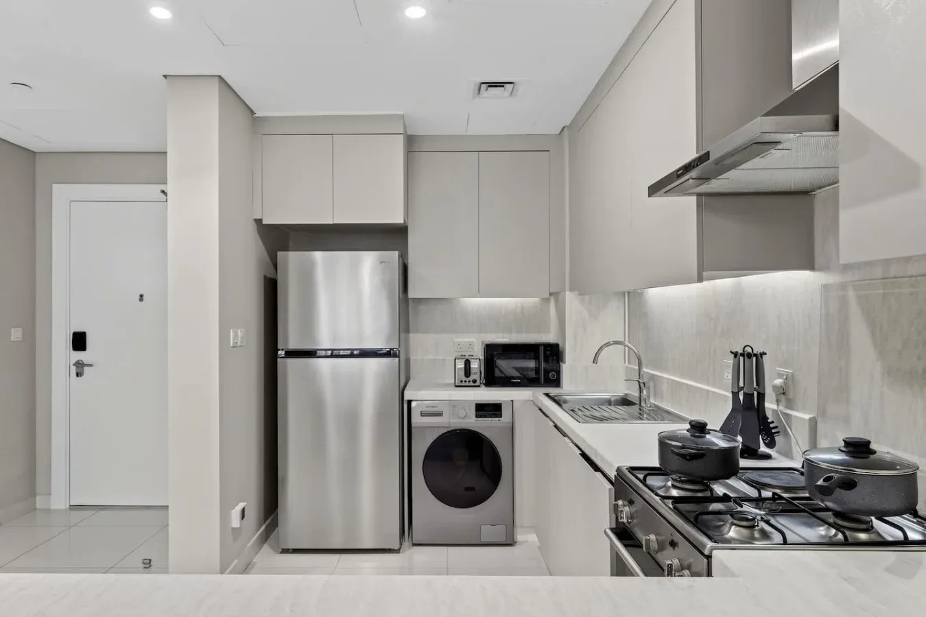 Una cocina compacta con electrodomésticos de acero inoxidable, fregadero y cocina de gas.