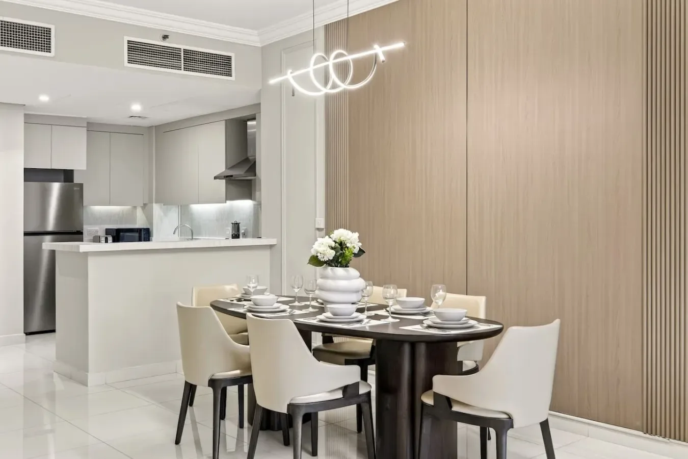 Un comedor con la mesa puesta y una cocina abierta al fondo.