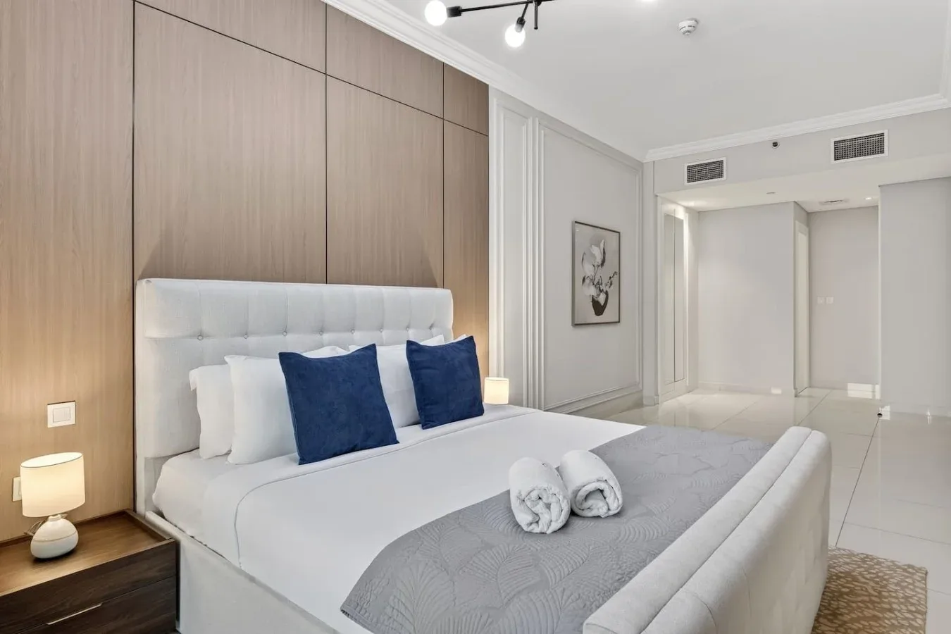 Un dormitorio con una cama tendida y cojines decorativos azules.