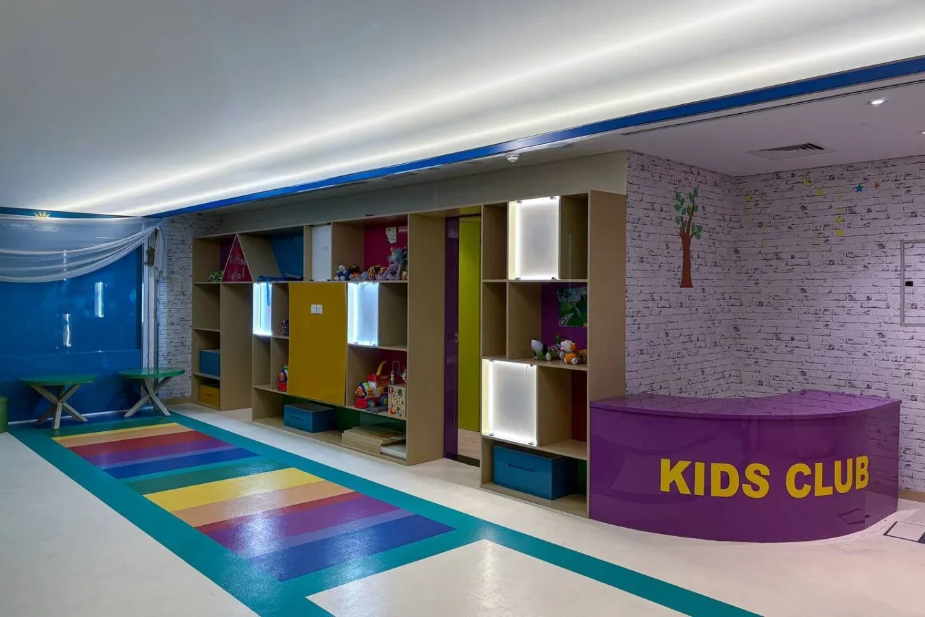 Una colorida sala de juegos infantil con juguetes y un mostrador del club infantil.