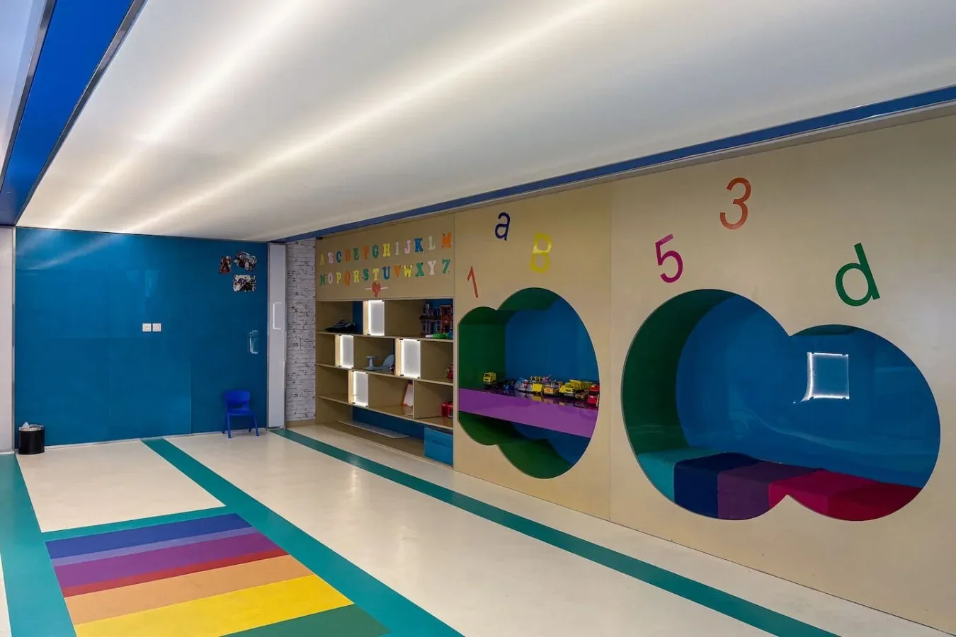 Una colorida sala de juegos infantil con letras decorativas y patrones geométricos brillantes en el suelo.