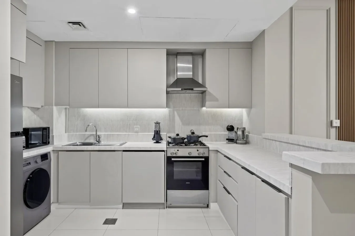 Una cocina moderna con gabinetes claros, una estufa y una encimera en forma de L.