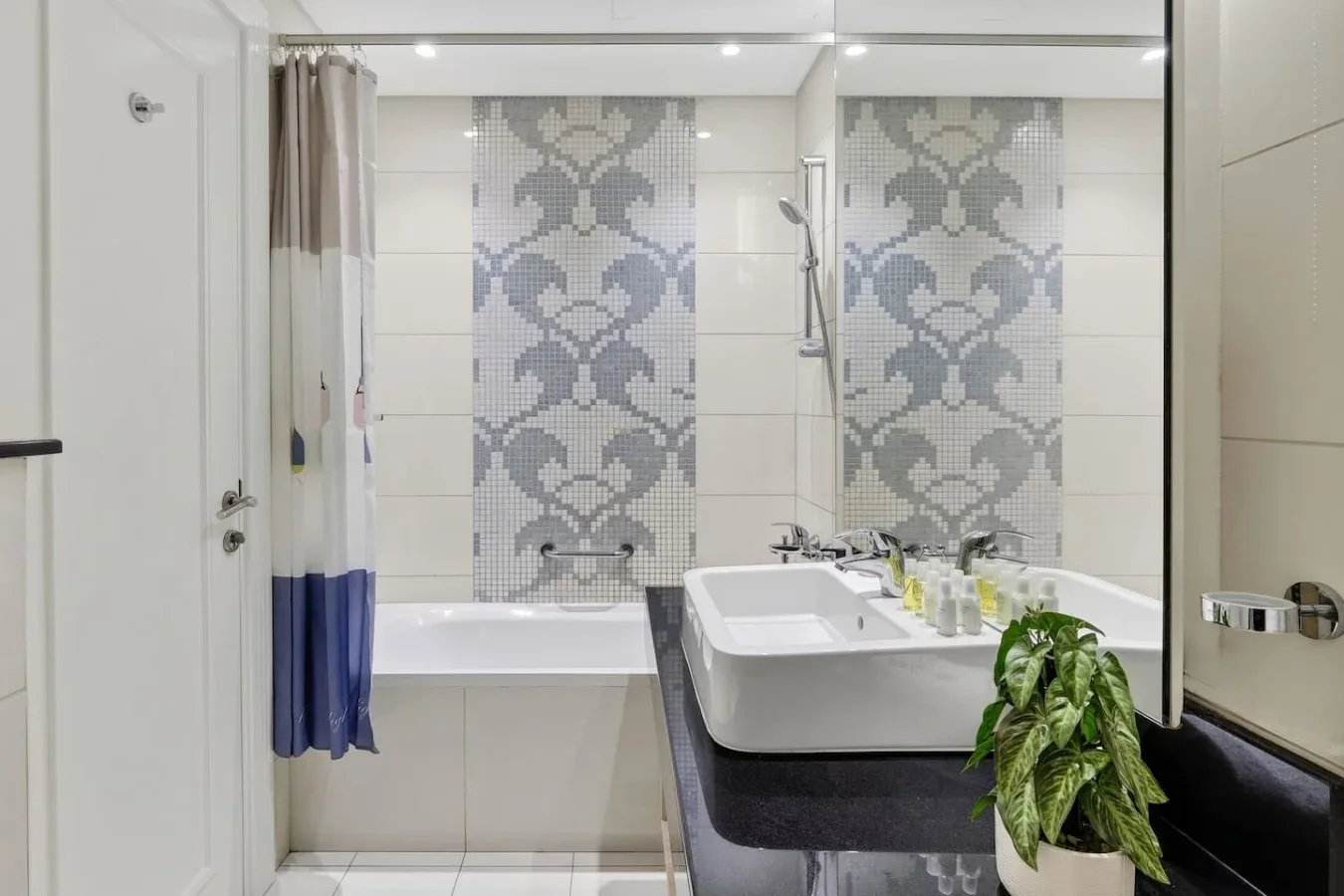 Un baño con bañera, lavabo y una pared de azulejos estampados.