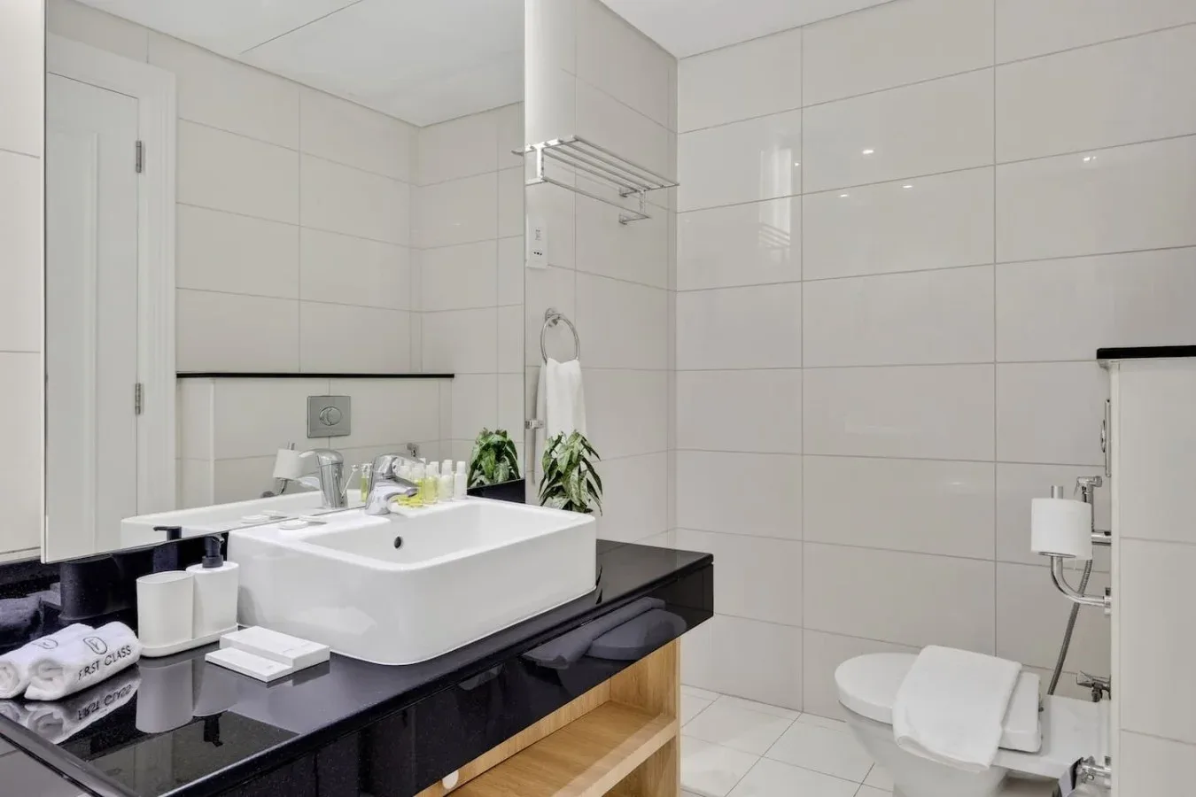 Un baño luminoso con azulejos, lavabo, inodoro y ducha.