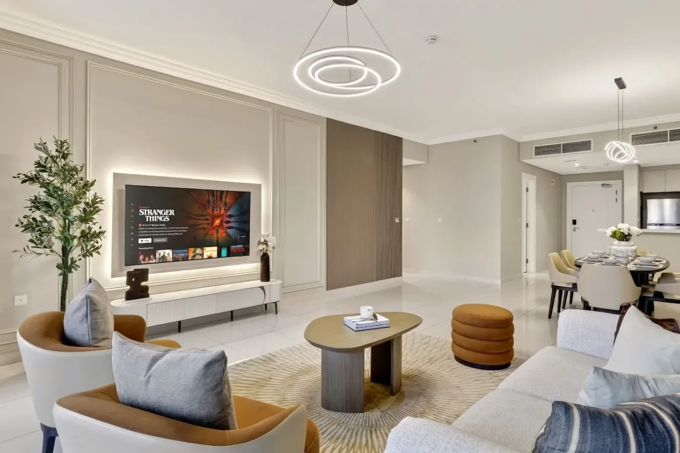 Una luminosa sala de estar y comedor con asientos, una mesa de centro y un televisor en la pared.