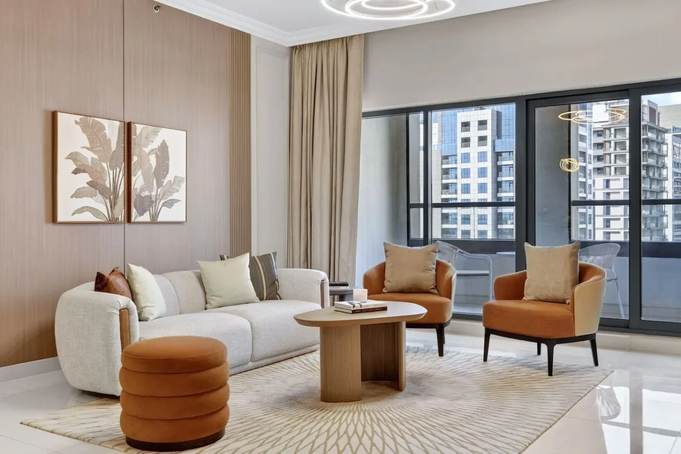Una sala de estar moderna con asientos alrededor de una mesa de centro junto a grandes ventanas.