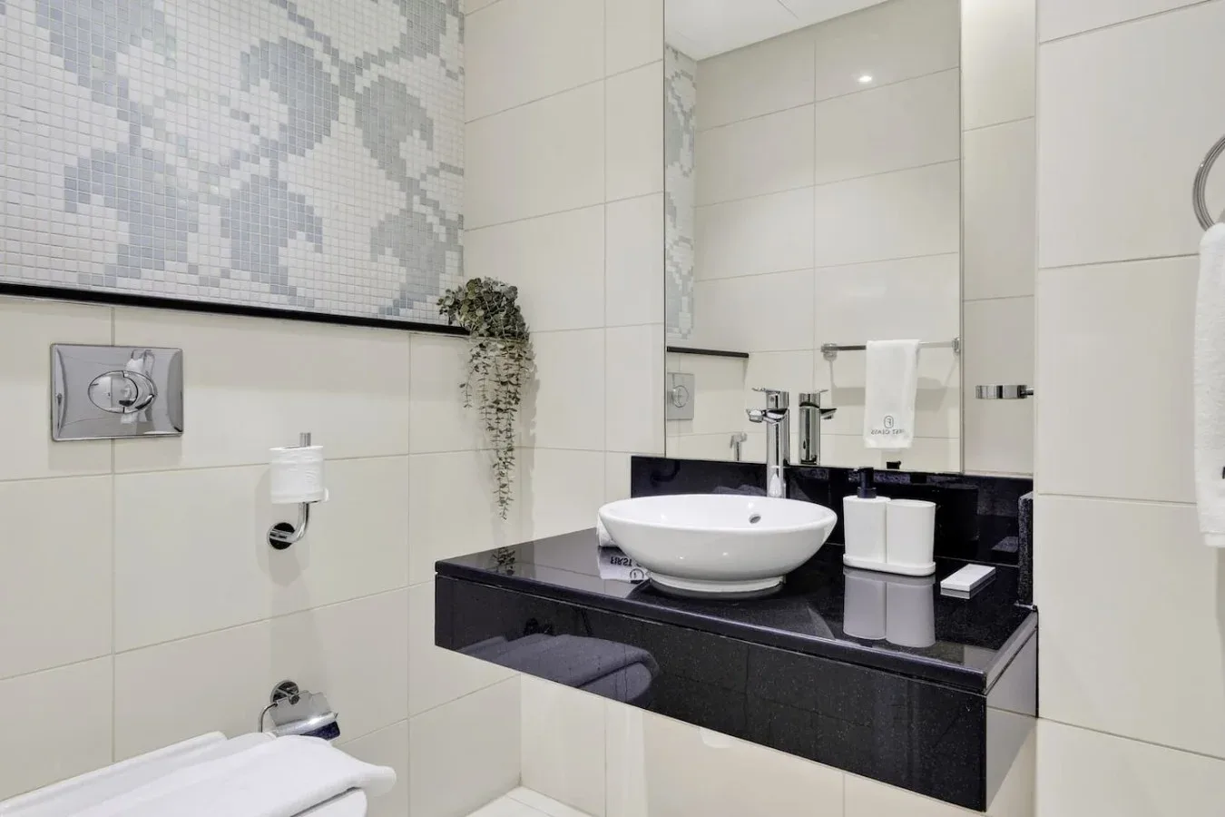Un baño alicatado con un lavabo sobre una encimera oscura.