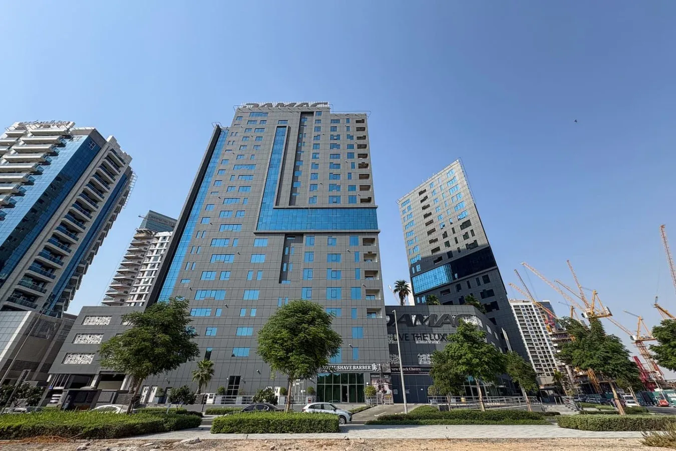 Edificios altos modernos bordean una calle urbana bajo un cielo azul despejado.