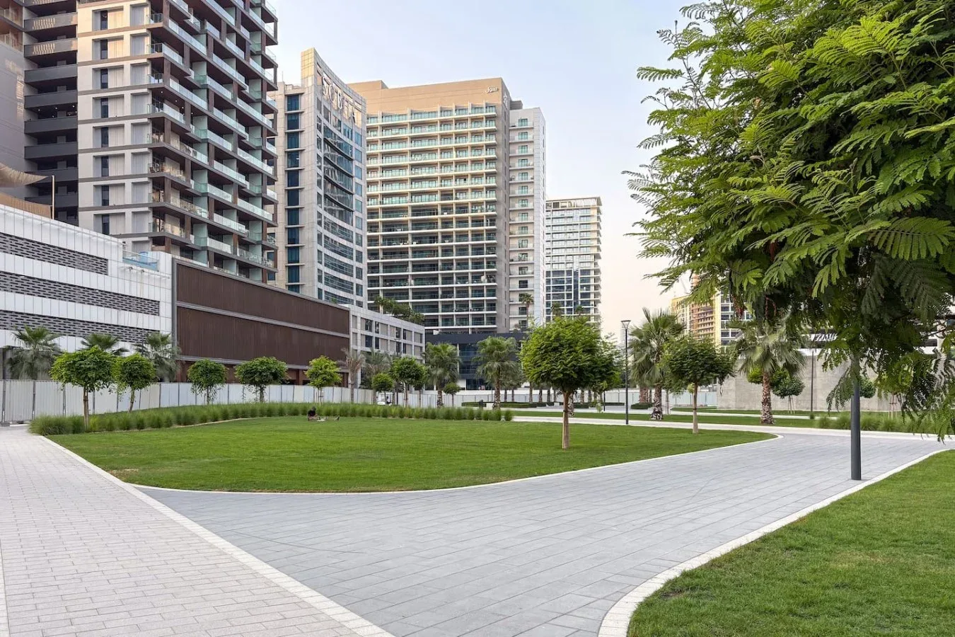 Un patio ajardinado con senderos pavimentados y edificios altos de apartamentos.