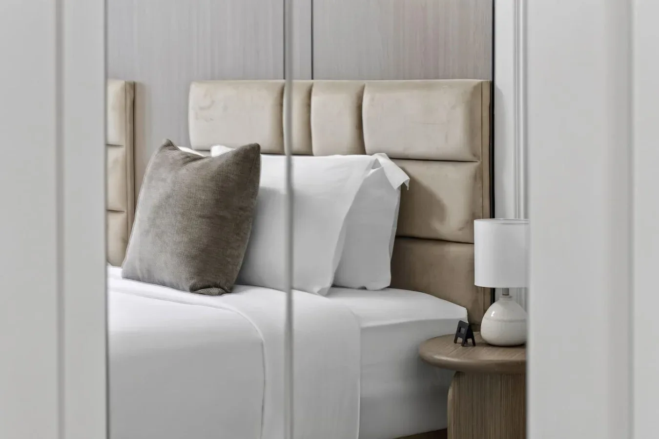 Un dormitorio con una cama bien tendida y ropa de cama en tonos neutros.