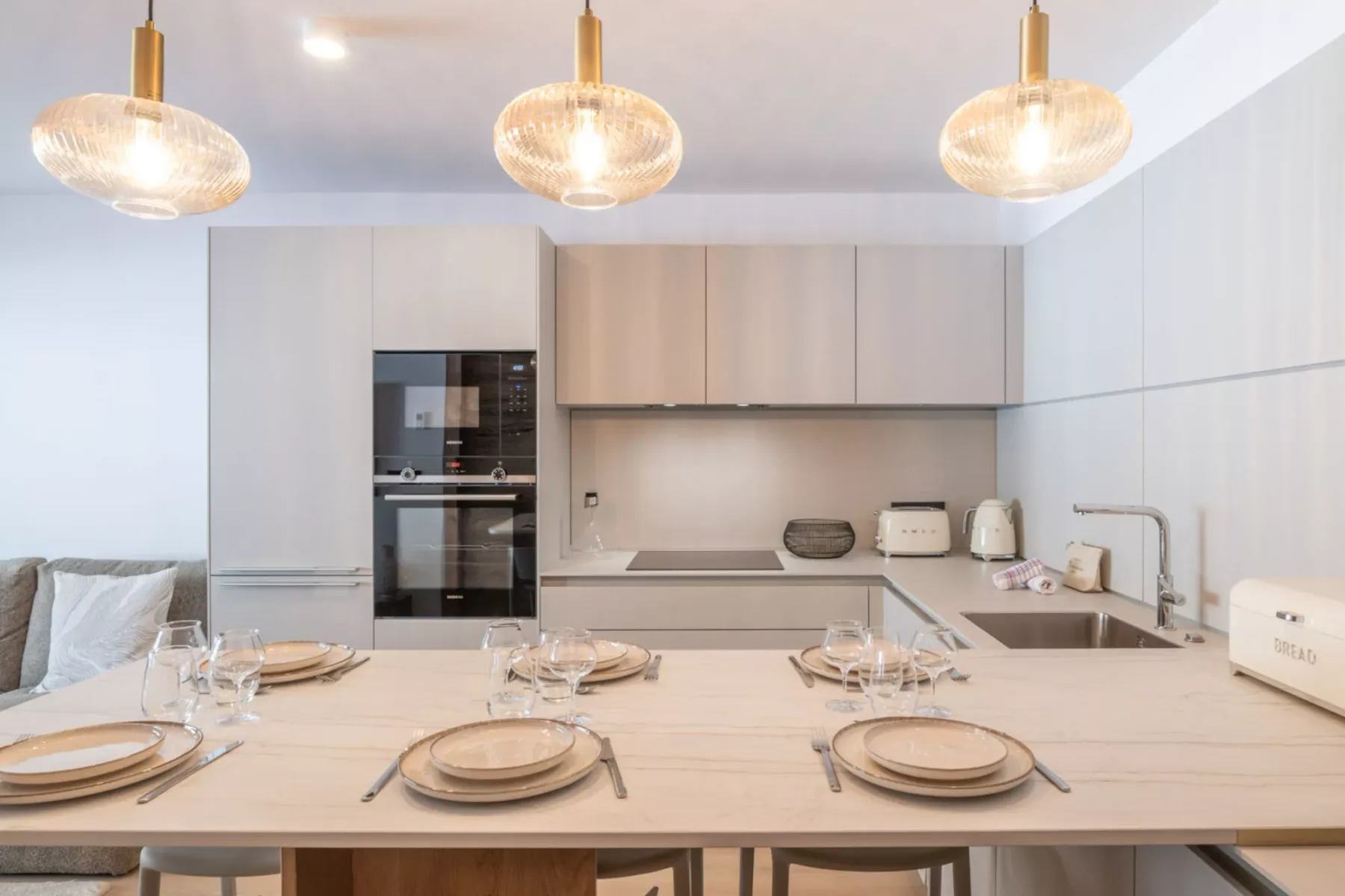 A modern kitchen with a dining table set with plates and glassware.