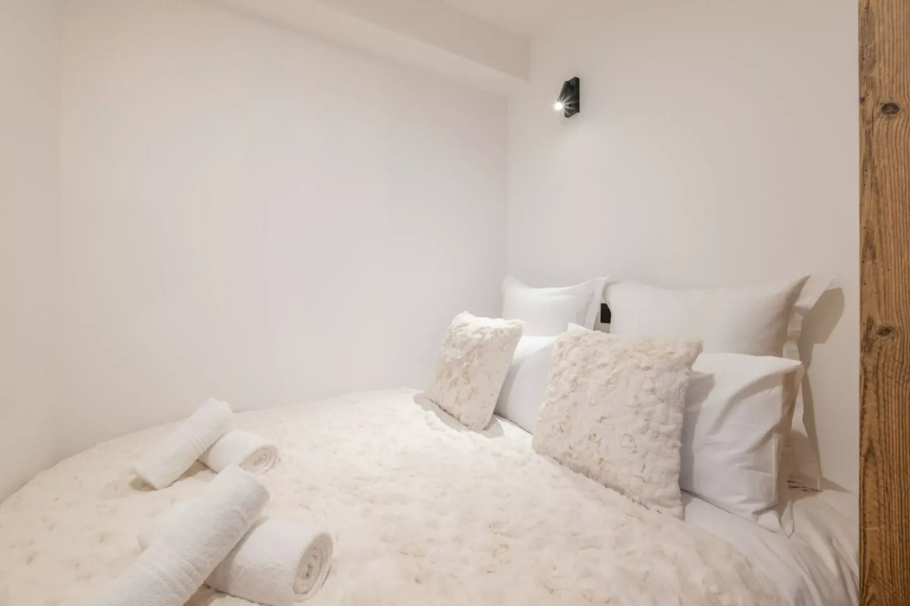 A bedroom with a bed dressed in white linens and textured pillows.