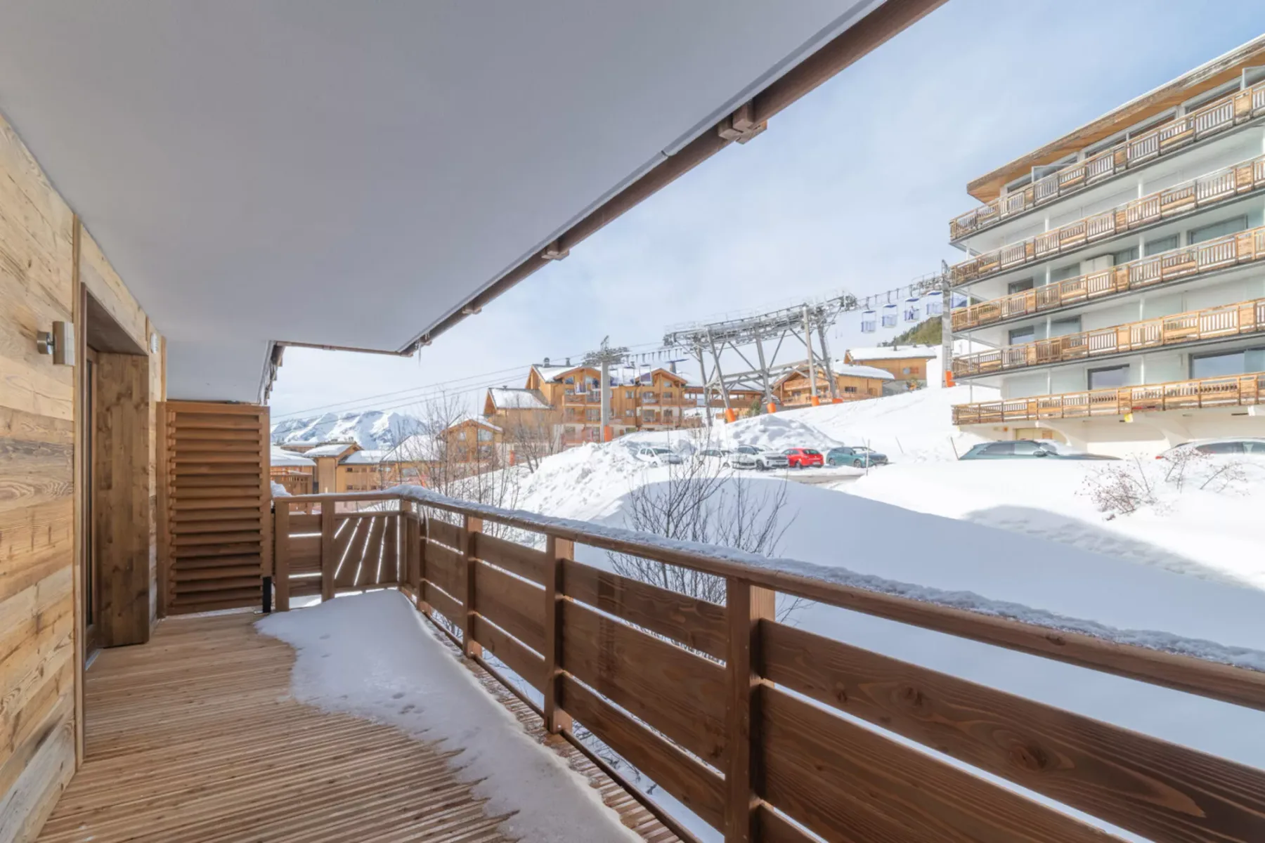 A balcony overlooks a snowy mountain resort and nearby buildings.