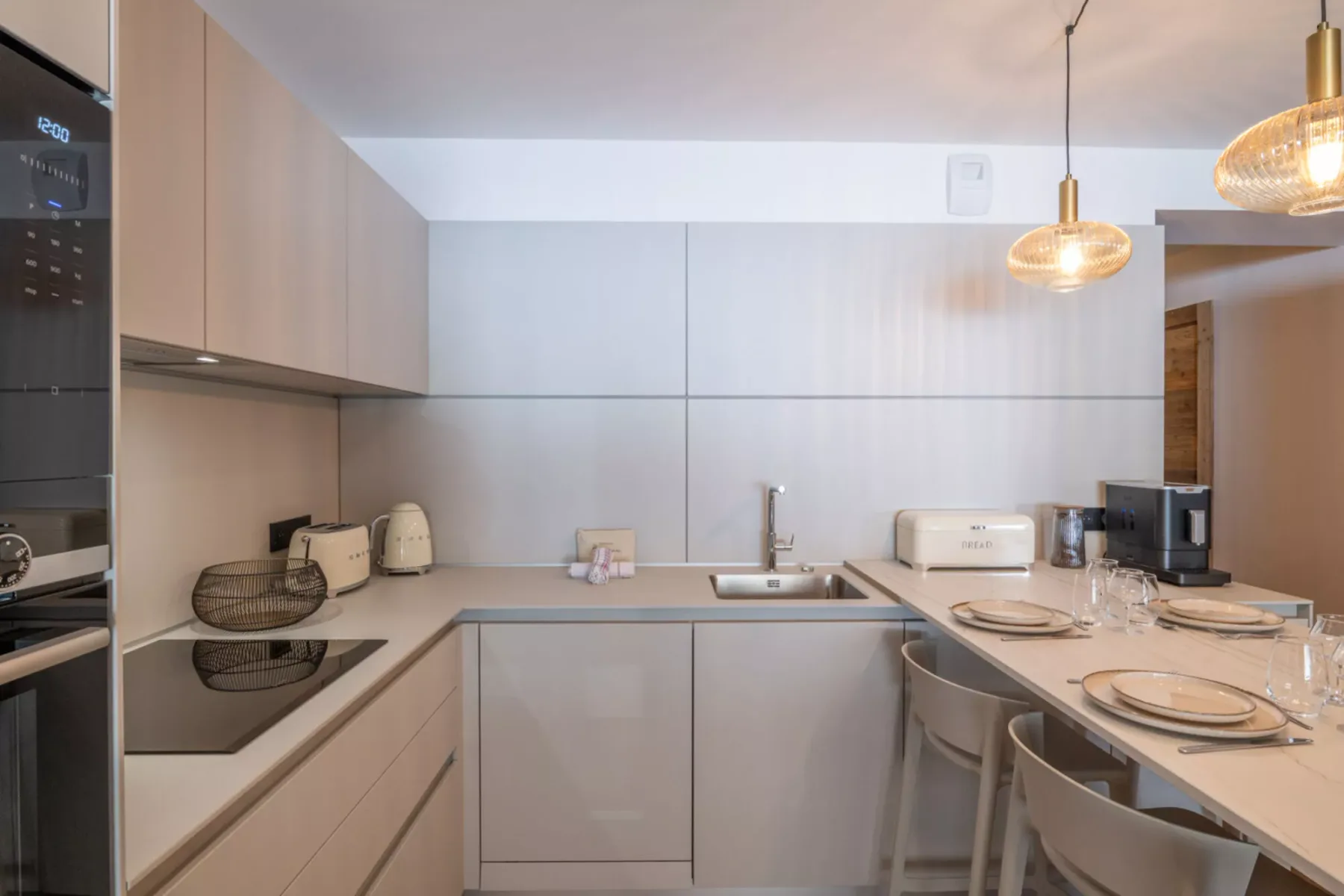 A modern kitchen with an L-shaped counter, sink, and dining seating.