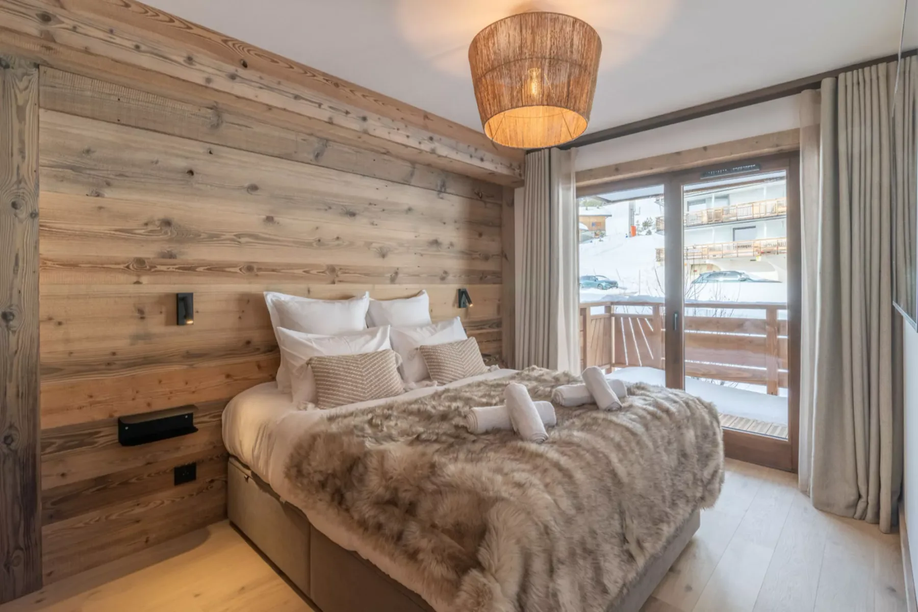 A bedroom with a bed and a glass door opening onto a balcony.