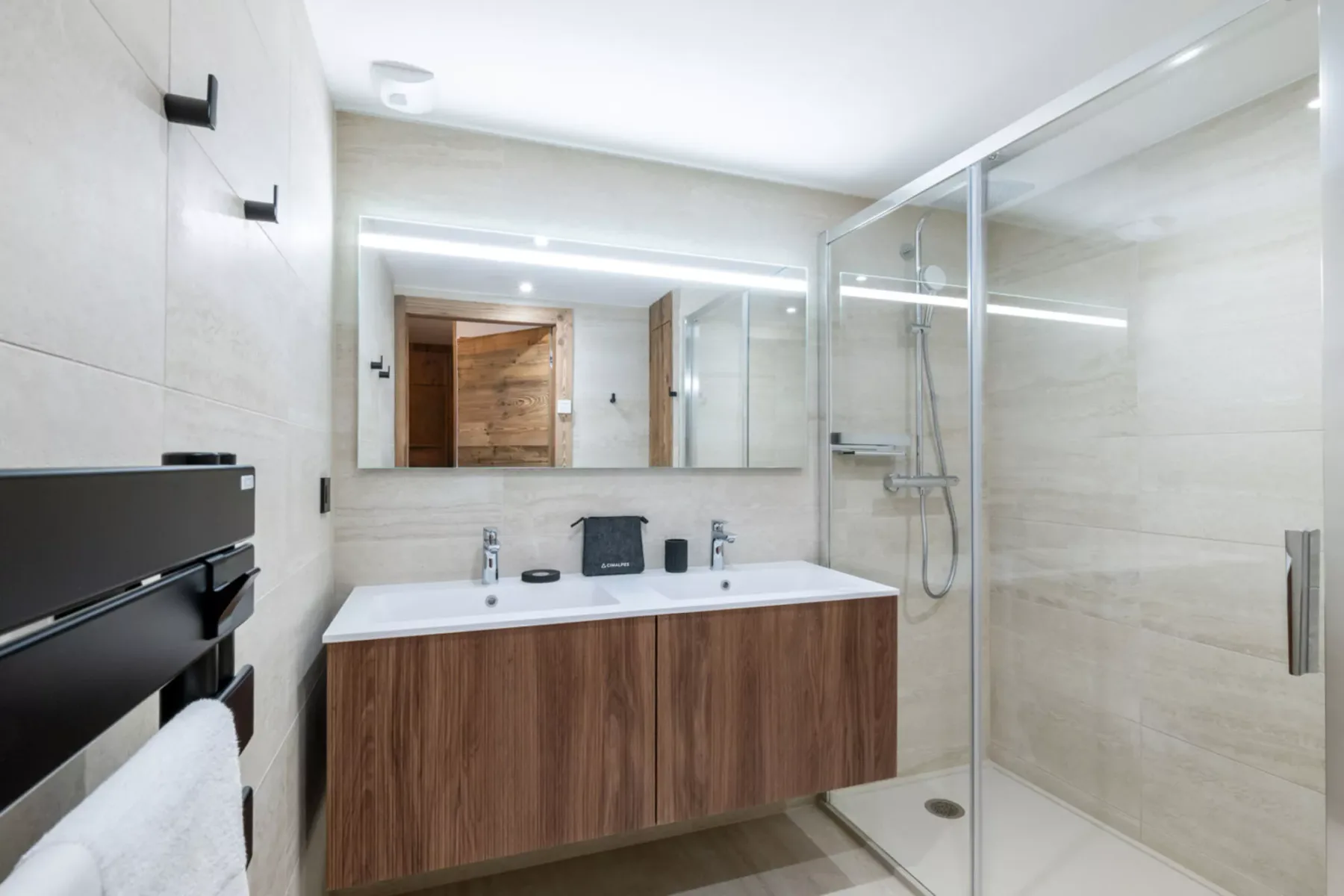A modern bathroom has a wide vanity and a glass-enclosed shower.