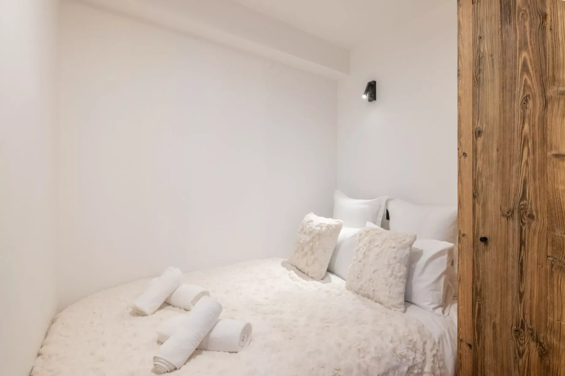 A bright bedroom with a bed dressed in white linens and pillows.