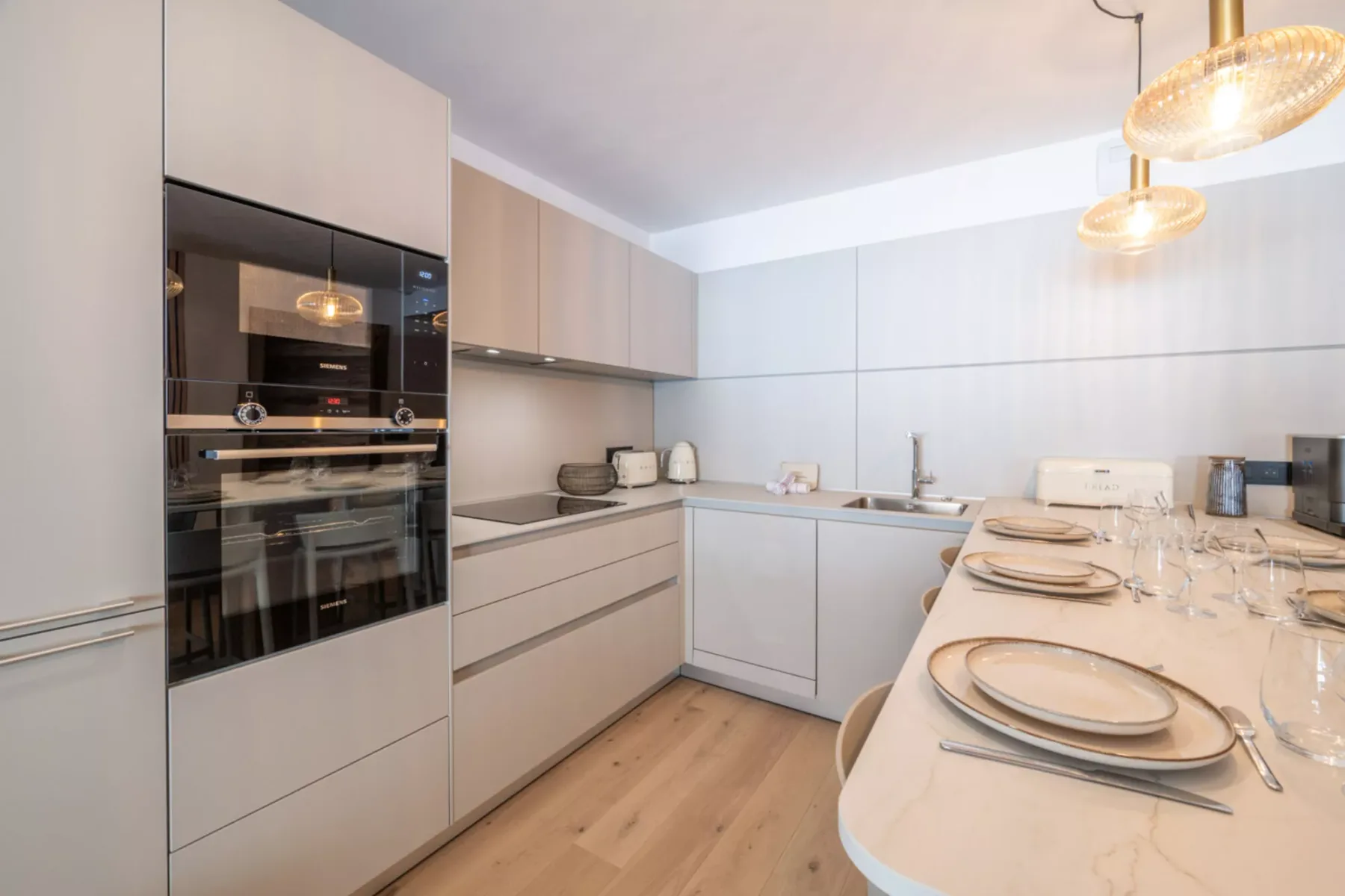 A modern kitchen with built-in appliances and a dining counter set with tableware.