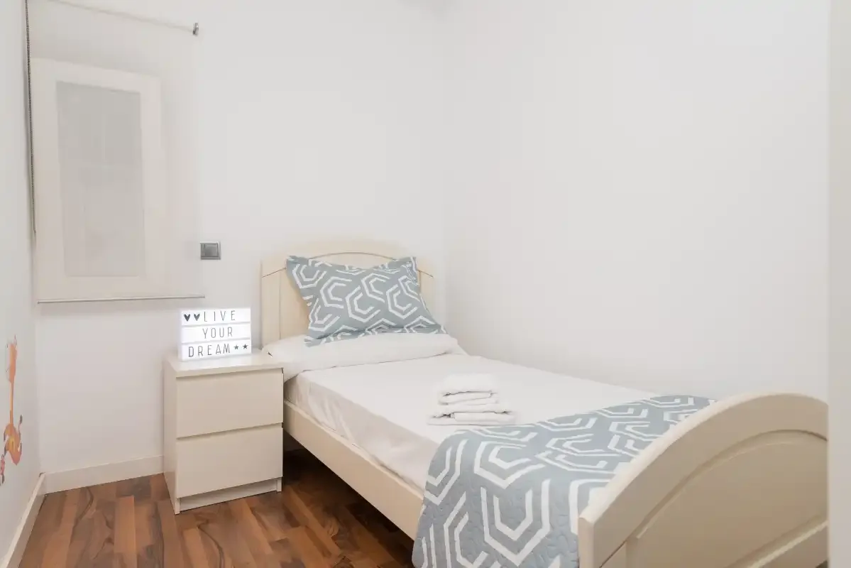 Un dormitorio luminoso con una cama individual y ropa de cama estampada.