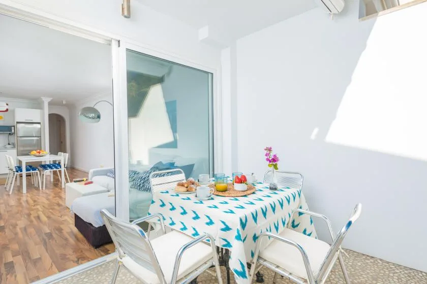 Un comedor luminoso con una mesa puesta junto a un gran separador de vidrio.