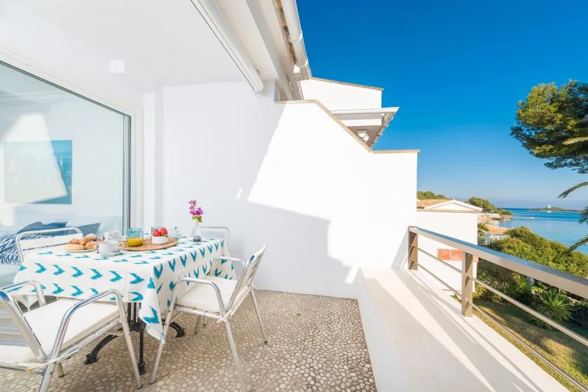 Una zona de comedor al aire libre da a un balcón con vistas al mar.