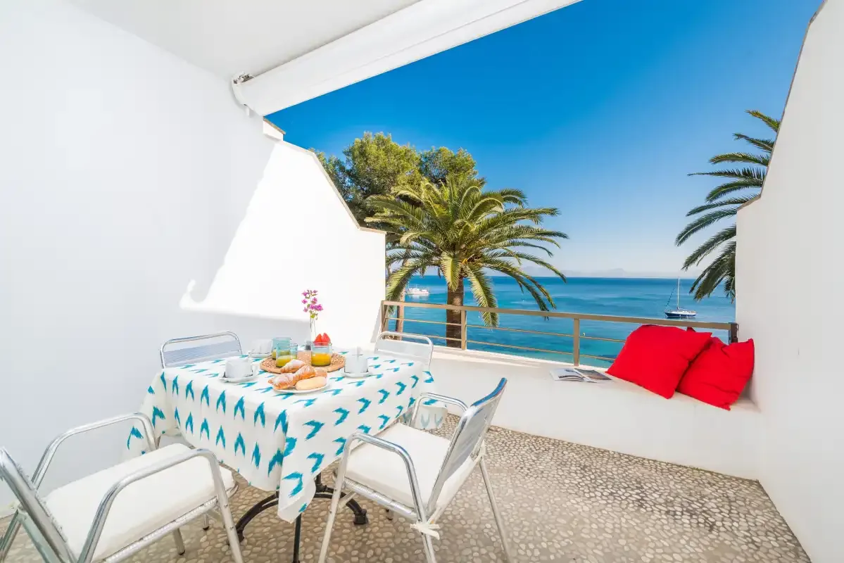 Una terraza junto al mar con una mesa y sillas frente al agua.