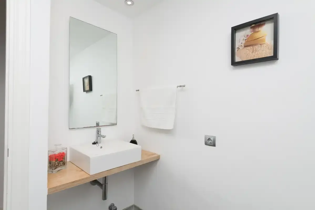 Un baño con un espejo de pared y un lavabo sobre una encimera de madera.