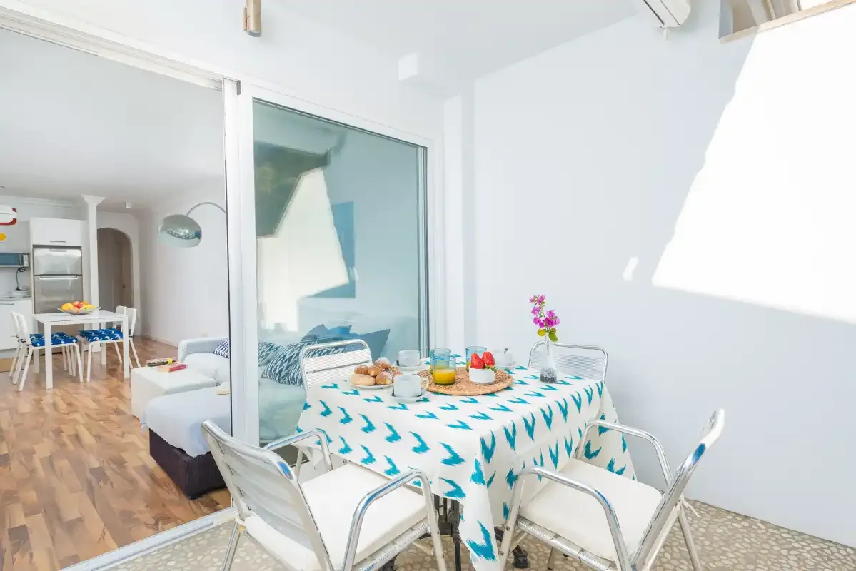 Comedor con un mantel estampado y una sala de estar contigua.