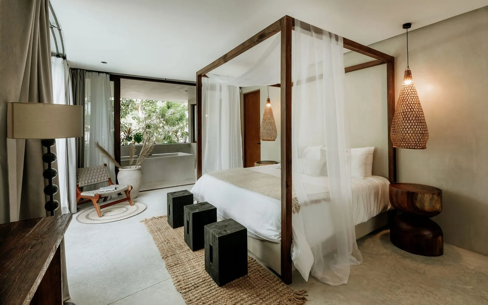 Un dormitorio con una cama con dosel y cortinas transparentes.