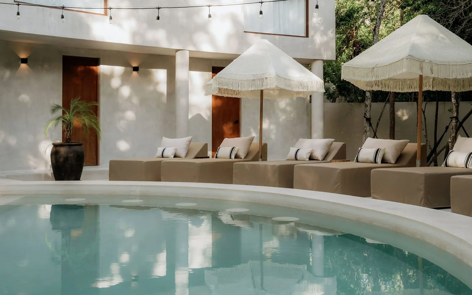 Una piscina al aire libre junto a asientos acolchados y sombrillas.