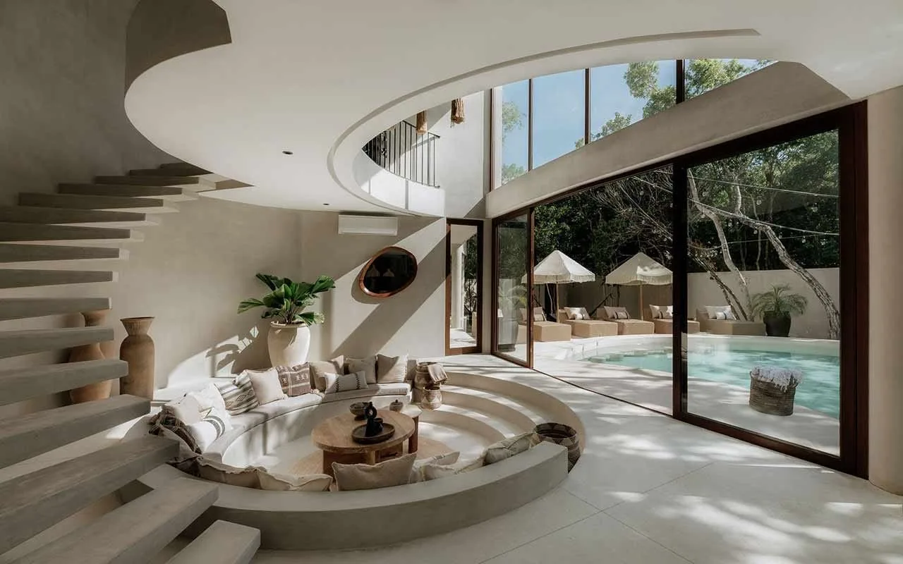 A curved living area with tiered seating opens onto a glass-walled pool courtyard.