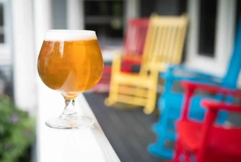 Glass of beer with colorful rocking chairs in the background