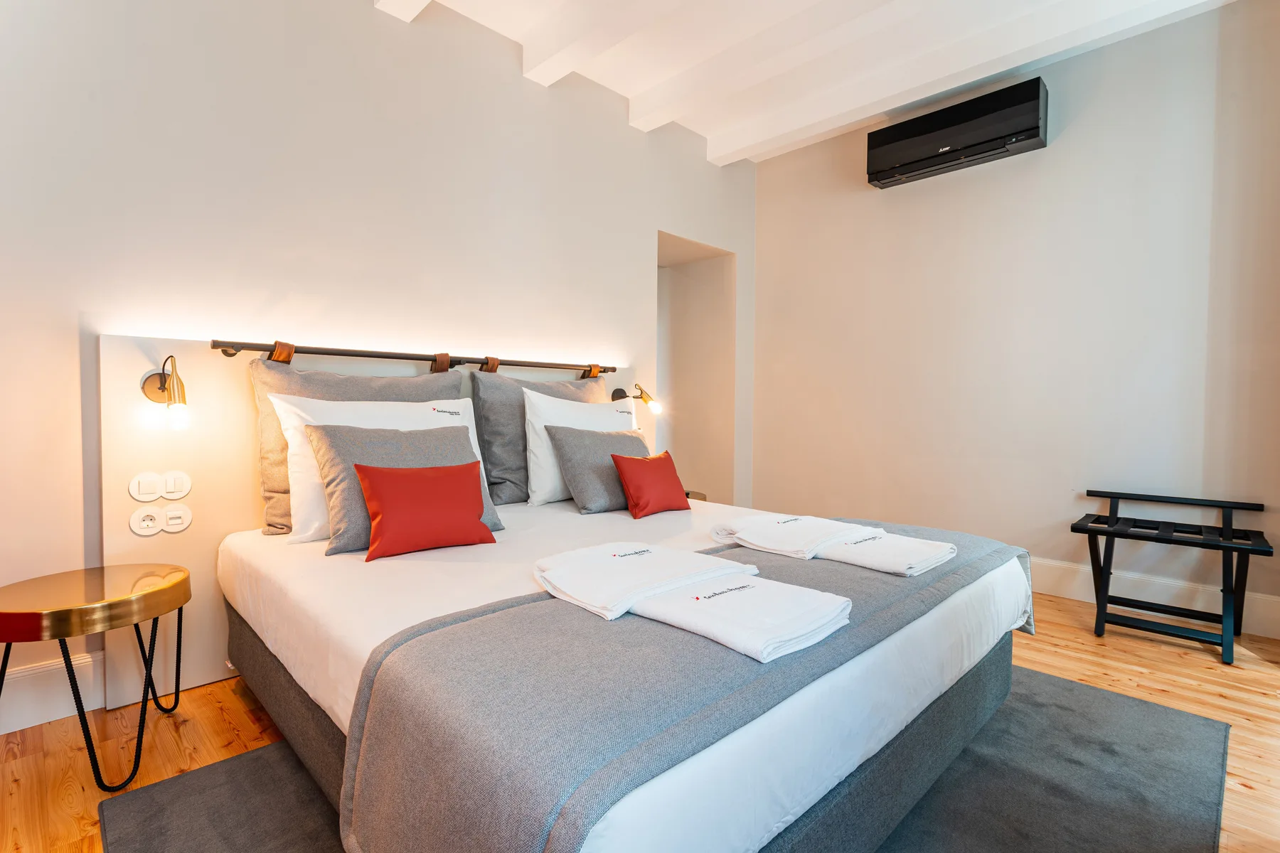 Un dormitorio con una cama bien arreglada y un aire acondicionado en la pared.