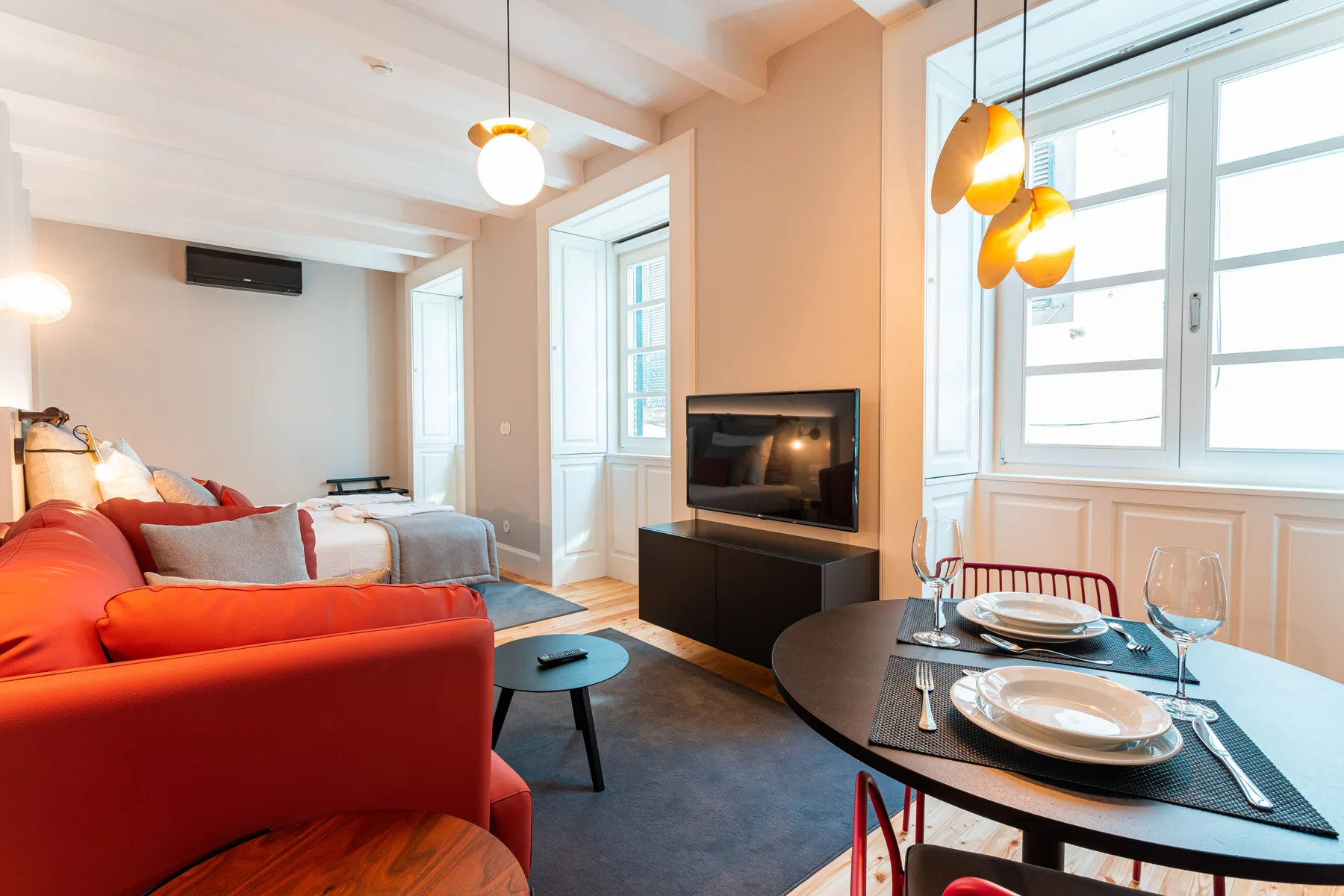 Una luminosa zona de estar y comedor con asientos rojos y una mesa puesta.