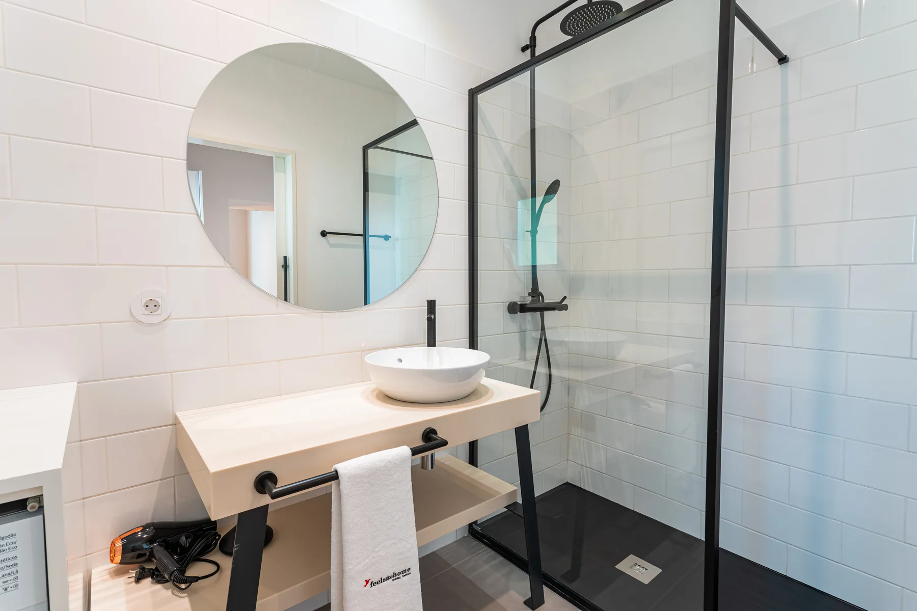 Un baño con azulejos, un lavabo suspendido y una ducha de cristal.